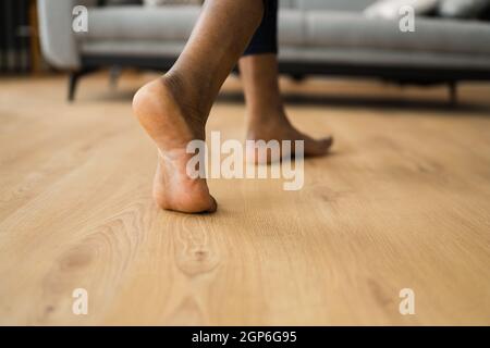 African Barefoot Frau Zu Fuß Auf Beheizten Boden Im Wohnzimmer Stockfoto