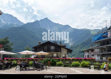 Courmayeur, Italien - August 24 2021: Restaurant oder Café mit Außenbereich in Norditalien. Sonnenschirme, Sonnenschirme mit Tisch und Stühlen und Berg Stockfoto