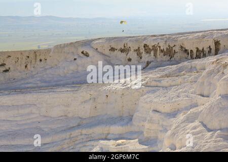 Zwei Personen schweben auf einem Doppelgleitschirm über die Travertinen von Pamukkale (kaskadierende Thermalbecken) in der Nähe der antiken griechischen Stadt Hierapolis in der Türkei. Stockfoto