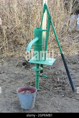 Handpumpe führt zu einem artesischen Brunnen. Pumpen von Wasser für die Bewässerung des Gartens. Stockfoto