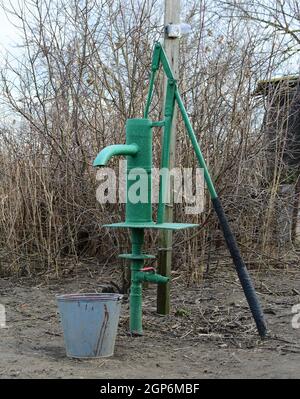 Handpumpe führt zu einem artesischen Brunnen. Pumpen von Wasser für die Bewässerung des Gartens. Stockfoto