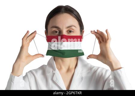 Atemschutzmaske mit Flagge von Ungarn Arzt setzt auf medizinische Gesichtsmaske isoliert auf weißem Hintergrund. Stockfoto