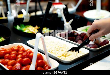 Hand hält Löffel zu Schaufel gekocht Job Tränen an Salatbar. Salatbuffet im Restaurant. Salatbuffet zum Mittag- oder Abendessen. Gesunde Ernährung. C Stockfoto