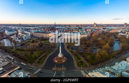 Erstaunlicher Luftpanorama zum Freiheitsdenkmal mit der Altstadt im Hintergrund, während des Herbstsonnenaufgangs. Milda - Freiheitsstatue mit drei Golden Stockfoto