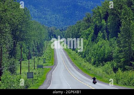 Motorradfahrer auf endlosem Highway ohne Verkehr, Trans Canada Highway, British Columbia, Kanada Stockfoto