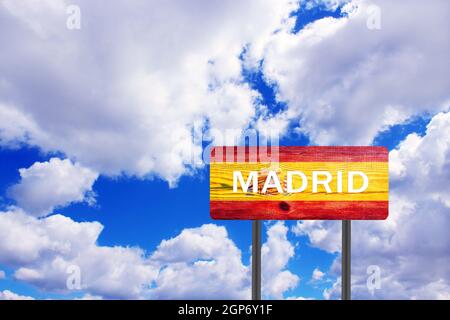 Schild auf Holzplatte mit Hinweis auf die Richtung nach Madrid mit Blick auf den bewölkten Himmel. Straßenschild auf Holztisch, das die Siedlung anzeigt. Melden Sie sich über Madrid an Stockfoto