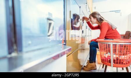Eine Frau wartet in einem Waschsalon vor einer Waschmaschine Stockfoto
