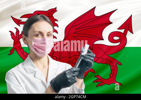 Ärztin bereitet die Impfung vor dem Hintergrund der Wales-Flagge vor. Impfkonzept Wales. Stockfoto