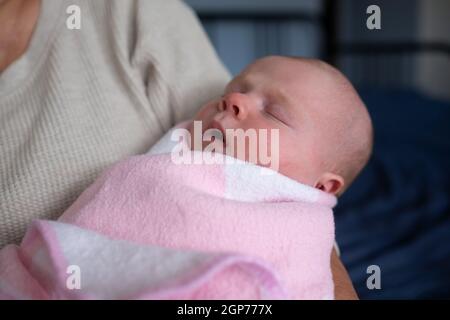 Ältere Großmutter, die ein Neugeborenes in den Armen hält Stockfoto