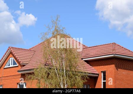 Das Haus mit einem Dach aus klassischen Fliesen. Dachziegel aus gebranntem Ton auf dem Dach gemacht. Stockfoto