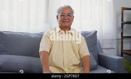 Kopf erschossen Porträt alter Mann Großvater Lächeln mit Brillen entspannend Blick auf die Kamera, asiatische glücklich Senior alten grauhaarigen sitzen im Wohnzimmer Stockfoto