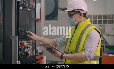 Asiatische Fabrik Arbeiter Mann Betrieb automatisierte Programmierung CNC-Frässteuerung Maschinenindustriezentrum in der Werkzeugwerkzeugherstellung Stockfoto