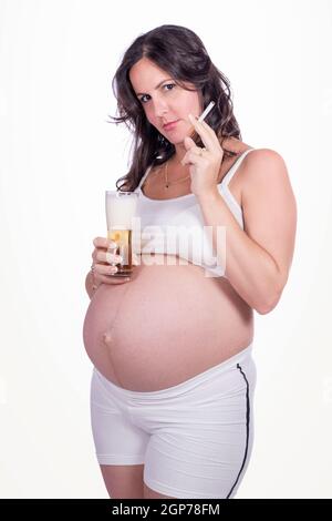 Eine Schwangere mit einer Zigarette in der einen Hand und einem Glas Bier in der anderen Stockfoto