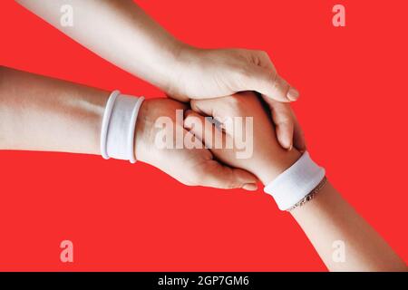 Helfende Hand an einen Freund. Weibliche Hände auf rotem Rückengrund. Stockfoto