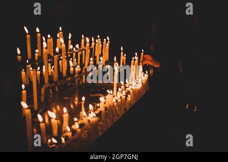 Kerze Flammen in der Kirche. Düstere Stimmung mit gebrannten Kerzen. Stockfoto