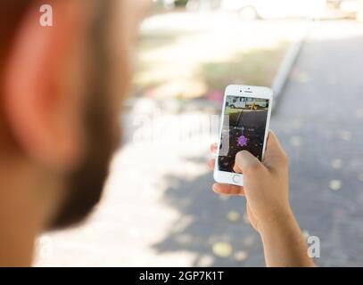 Empoli, Italien - 26. Juli 2016: Nintendo Pokemon WIRD AUGMENTED Reality-Smartphone. Der Spieler im Park mit der Hand berührt den Bildschirm, während er fängt Stockfoto