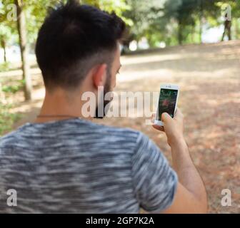 Empoli, Italien - 26. Juli 2016: Nintendo Pokemon WIRD AUGMENTED Reality-Smartphone. Der Spieler im Park mit der Hand berührt den Bildschirm, während er fängt Stockfoto