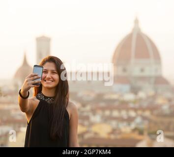 Young Teen nimmt eine Selfie bei Sonnenuntergang in Florenz, Dom Santa Maria del Fiore im Hintergrund. Stockfoto