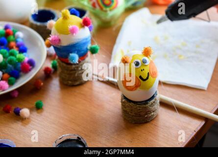 Bemaltes osterei mit geklebten Augen steht auf dem Tisch Stockfoto