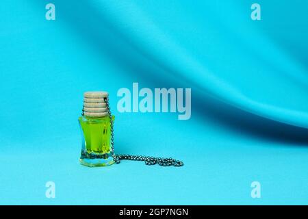 Luftduft. Eine Glasflasche mit einer gelben Flüssigkeit, einem Holzstopfen auf einem welligen blauen Hintergrund. Selektiver Fokus. Stockfoto