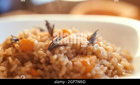 Kürbisrisotto, Rezept mit Reis und Kürbis auf rustikalem Tisch mit Zutaten. Herbst und Halloween Rezept. Stockfoto