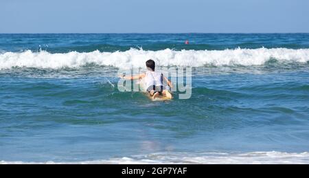 Surfer auf Longboard reitet eine schöne blaue Welle im Meer. Stockfoto