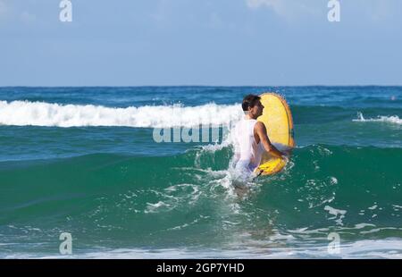 Surfer auf Longboard reitet eine schöne blaue Welle im Meer. Stockfoto