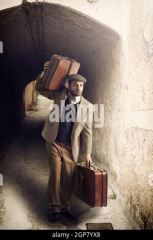 Emigrant Mann mit dem Koffer in einer kleinen Stadt. Stockfoto