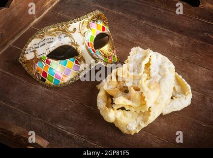 Typische frittiertes Gebäck der italienischen Karneval mit venezianische Maske. Diese süssen werden auf unterschiedliche Weise, chiacchiere, Galani, cenci oder Frappe genannt. Stockfoto