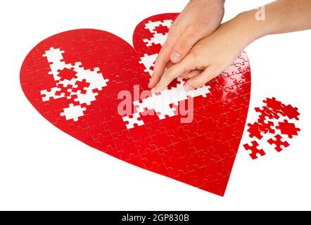 Junges Paar Montage ein rotes puzzle Herzform auf weißem Hintergrund. Stockfoto