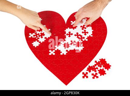 Junges Paar Montage ein rotes puzzle Herzform auf weißem Hintergrund. Stockfoto