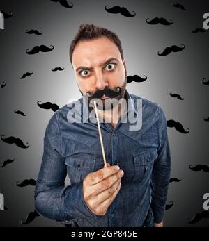 Junger Mann mit Fotokabine geformt, Schnurrbart und Hintergrund mit kleine Schnurrbärte Stockfoto