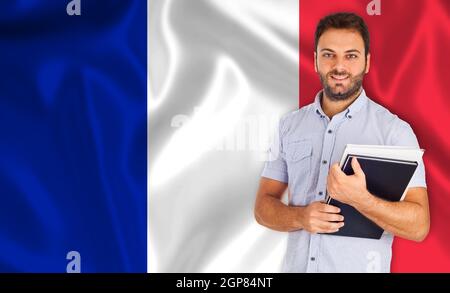 Lächelnde junge männliche Schüler über französische Flagge Stockfoto