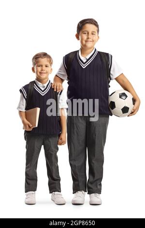 In voller Länge Porträt von zwei Schuljungen tragen Schuluniformen und halten einen Fußball isoliert auf weißem Hintergrund Stockfoto