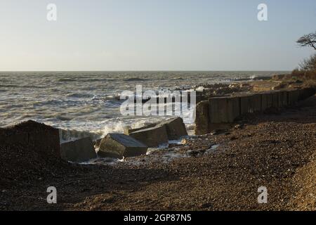 Stürmisches Wetter mit Wellen am Kiesstrand bei Climping in der Nähe von Littlehampton, West Sussex, England. Sturmschäden an der Küstenabwehr. Stockfoto