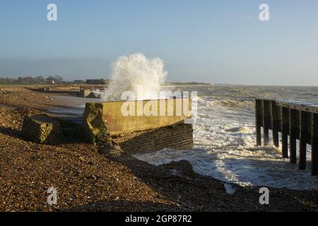 Stürmisches Wetter mit Wellen am Kiesstrand bei Climping in der Nähe von Littlehampton, West Sussex, England. Sturmschäden an der Küstenabwehr. Stockfoto