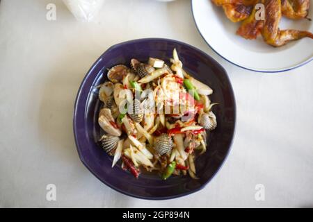 Thai-Essen, Papaya-Salat Herzmuscheln auf dem Teller Stockfoto