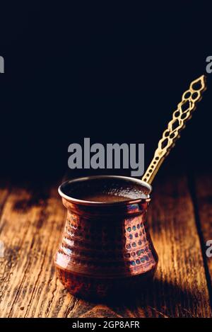 Türkischer Kaffee. Gebrühten Kaffee in Kupfer cezve auf Holz- Oberfläche Stockfoto
