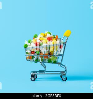 Gefrorenes Gemüse in Spielzeug-Warenkorb auf blauem Hintergrund sortiert. Voll von verschiedenen gefrorenen Gemüse Lebensmittel-Shop Trolley. Quadratisches Zuschneiden Stockfoto