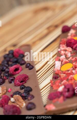 Verschiedene Arten von Schokolade mit getrockneten Früchten auf einem Holzbrett Stockfoto