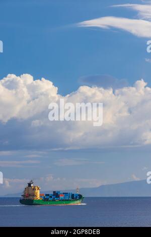 Frachtschiff in der Nähe Capo Peloro Leuchtturm in Punta del Faro an der Straße von Messina, nordöstlichste Landzunge von Sizilien, Italien Stockfoto