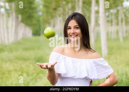 Close up Portrait von netten jungen Frau werfen Green Apple in der Luft im Freien. Stockfoto