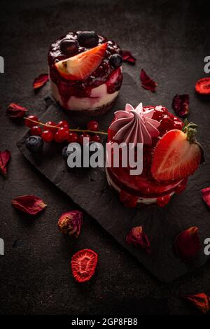 Runder klassischer Mini-Käsekuchen mit Fruchtgelee auf schwarzem Schiefer Stockfoto