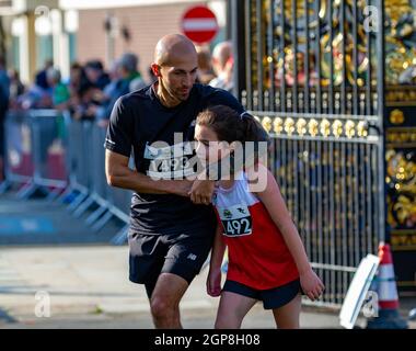 Warrington Running Festival 2021 - das junge Mädchen überquert die Ziellinie mit ihrem Vater, der sie umarmt Stockfoto