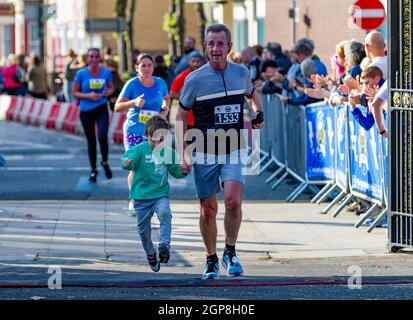 Warrington Running Festival 2021 - reifer Läufer überquert die Ziellinie mit einem kleinen Jungen Stockfoto