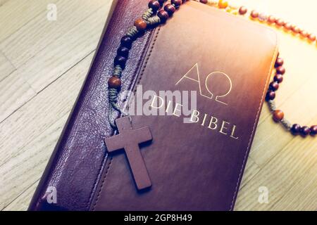 Bibel und Rosenkranz liegen auf einem Schreibtisch aus Holz Stockfoto