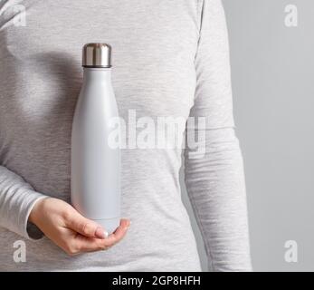 Nahaufnahme der Frau in grau T-Shirt mit gelb isoliert Flasche auf grauem Hintergrund Stockfoto