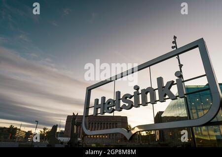 Helsinki-Schild bei herrlicher Nacht am Kansalaistori-Platz. Logo von Helsinki, der Hauptstadt Finnlands, über dem Abendhimmel. Stockfoto