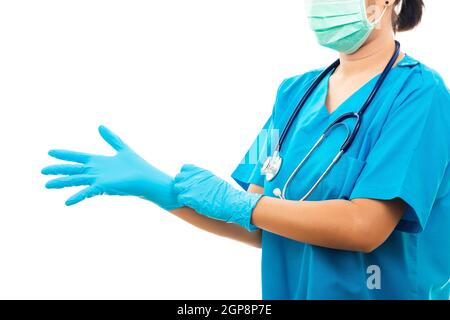 Krankenschwester steht mit Stethoskop setzt auf Gummihandschuhe und trägt medizinische Gesichtsmaske, Frau Arzt in blauer Uniform, Studio erschossen auf über isoliert Stockfoto