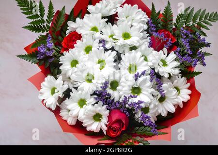 Ein wunderschön gestalteter Strauß aus weißen Chrysanthemen und roten Rosen auf hellem Hintergrund. Draufsicht, Nahaufnahme. Stockfoto